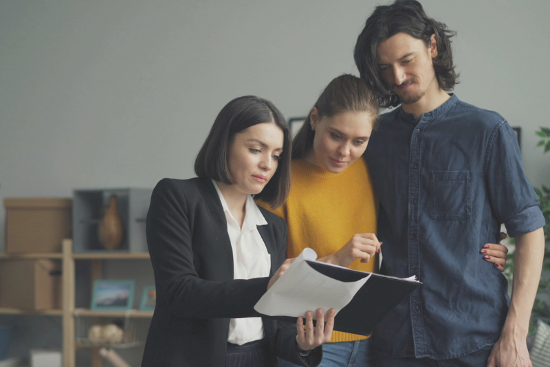 Couple listening to an agent explain contract details showing Confero's customer experience research services in real estate and housing industries.
